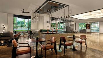 A spacious, modern lounge area with a bar, seating arrangements, and large windows offering views of the outdoors.