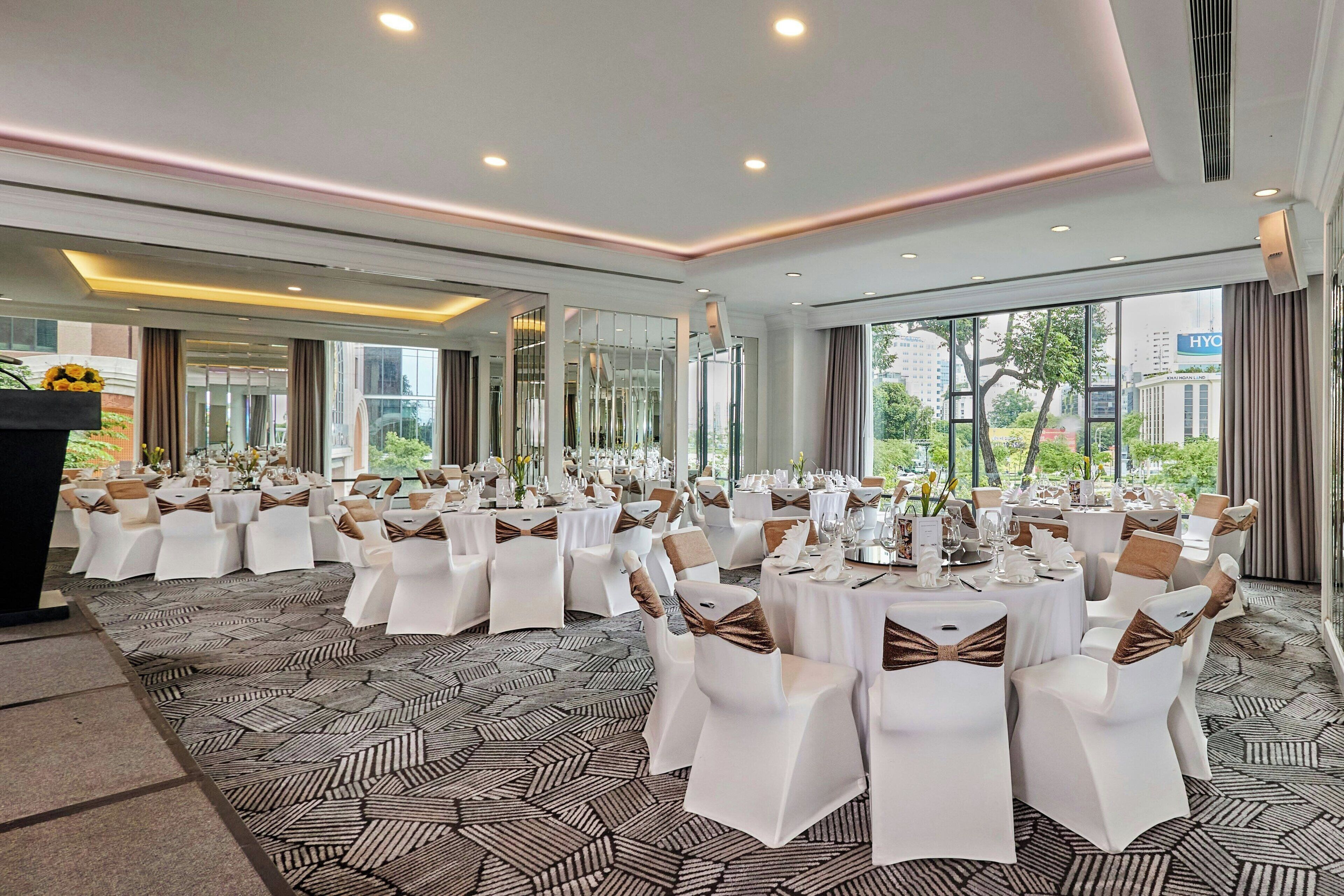 A conference room with round tables and chairs, large windows, and a patterned carpet.
