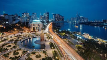 A cityscape at night with a prominent roundabout, a body of water, and high-rise buildings.