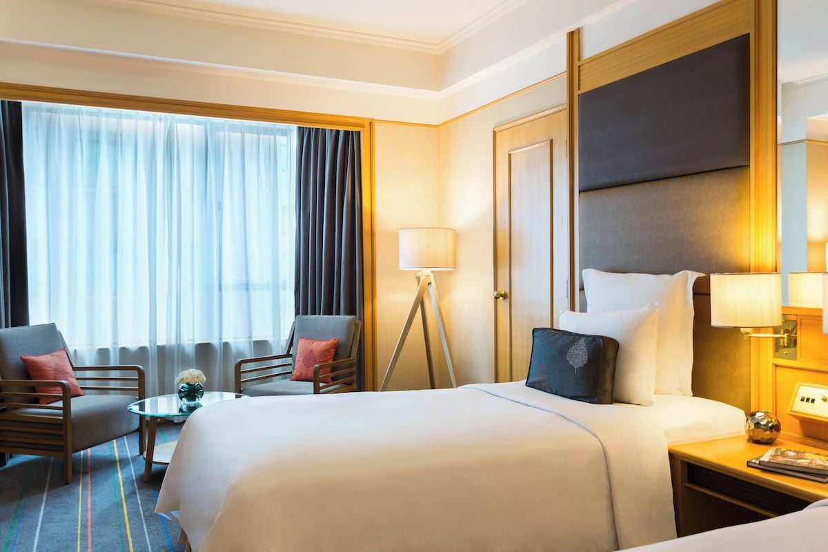 A hotel room with a large bed, two armchairs, a small table, and a lamp.