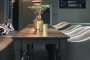 Une table de conférence ornée d’une plante en pot, d’une bougie et d’un panneau indiquant les directions pour se rendre aux différentes salles.