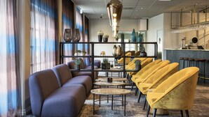 Un espace de détente moderne avec un canapé, des tables rondes et des chaises jaunes.