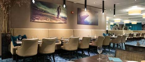A restaurant with a long counter, booths, and high ceilings.