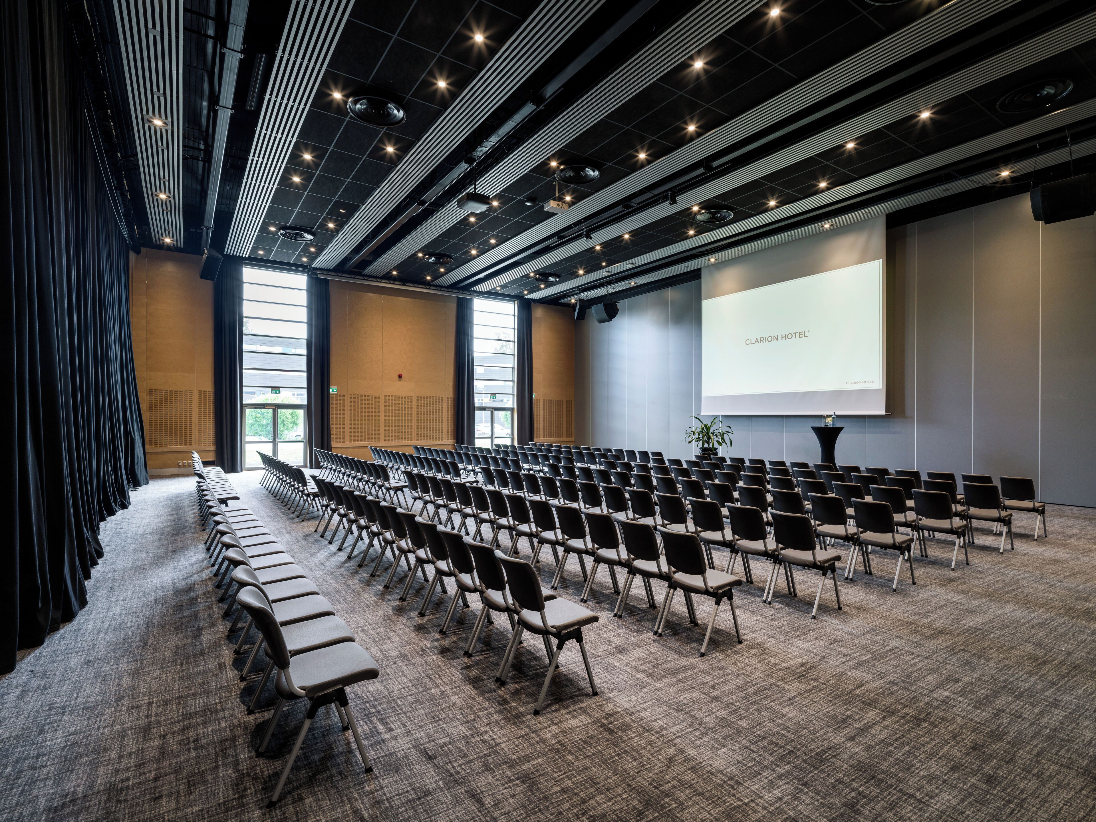 A conference room with rows of chairs, a projector screen, and a large window.