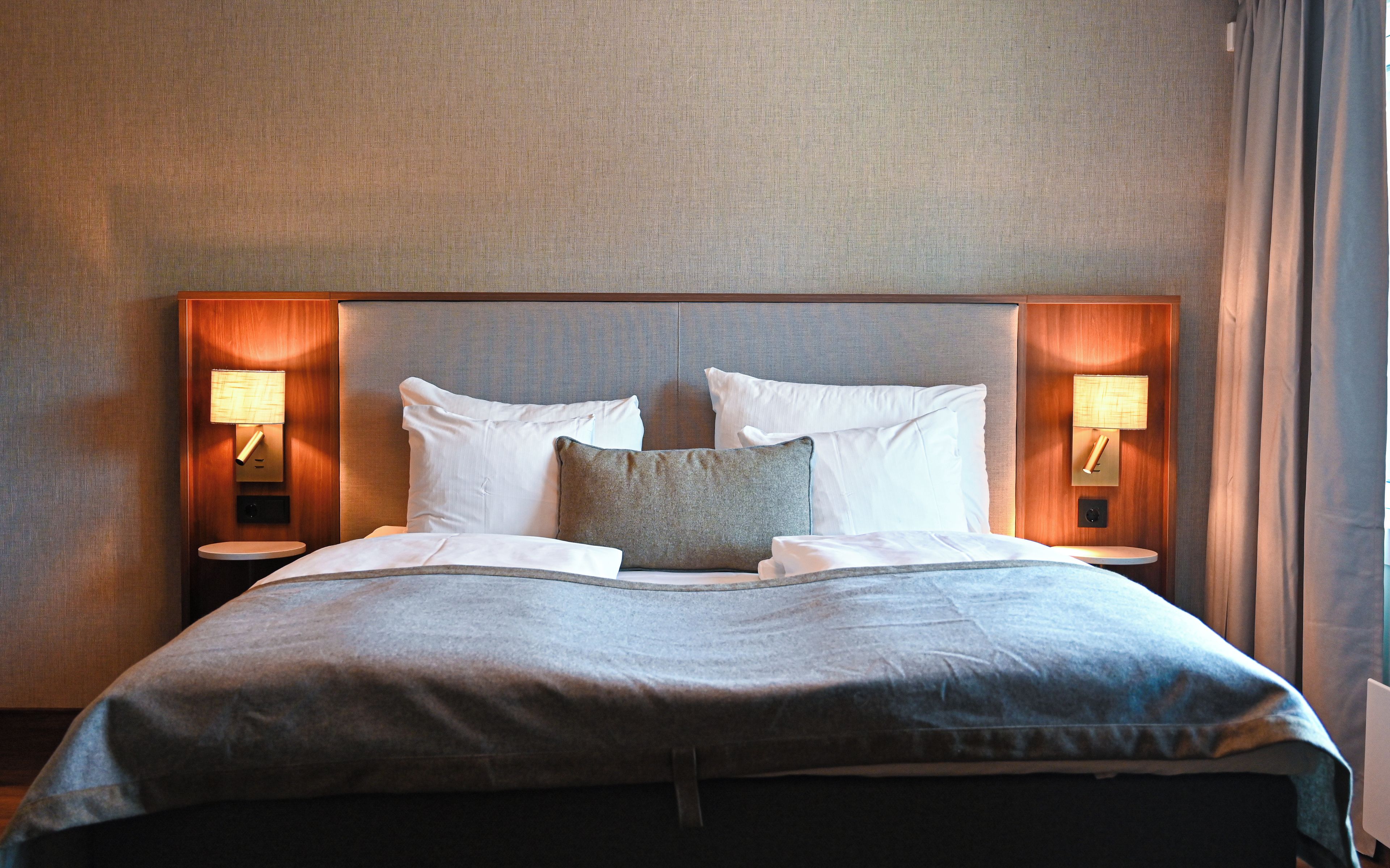 Une chambre d’hôtel avec un grand lit, deux lampes de chevet et une tête de lit.