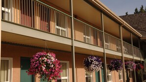 A building with a balcony, hanging flower baskets, and a door with a green frame. - Lakeview Inns & Suites - Hinton (Hinton)