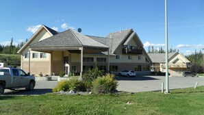 A two-story building with a covered patio area, a parking lot, and a small garden in front. - Lakeview Inns & Suites - Hinton (Hinton)
