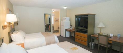 A hotel room with two beds, a desk, a television, and a mirror.