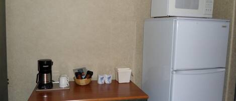 Una kitchenette equipada con microondas, cafetera y un refrigerador pequeño.
