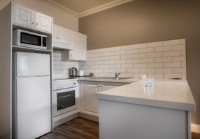 Una cocina moderna con armarios blancos, microondas, refrigerador, horno y lavaplatos.
