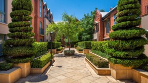 Un patio con jardines simétricos, edificios de ladrillo y cielo despejado.