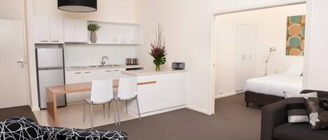 A compact living space with a kitchenette, a dining area, a bed, and a sofa.