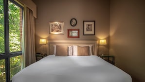 A neatly made bed with a white duvet, two bedside lamps, and framed artwork on the wall.