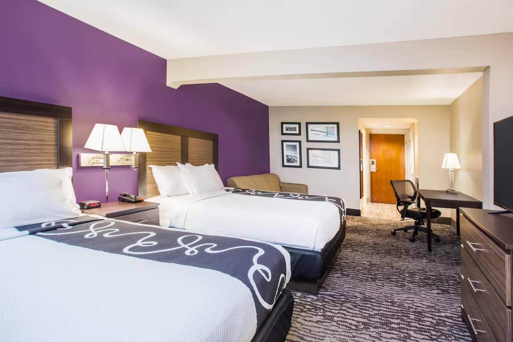 Une chambre d’hôtel avec deux lits, un bureau, une chaise et un téléviseur.