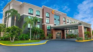 Un hotel Comfort Inn & Suites con diseño moderno, que cuenta con una entrada cubierta y un jardín delantero ajardinado.