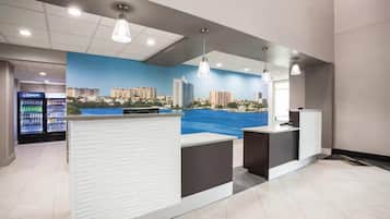 Une salle d'attente avec une fresque représentant un paysage urbain, un réfrigérateur Pepsi et un comptoir.