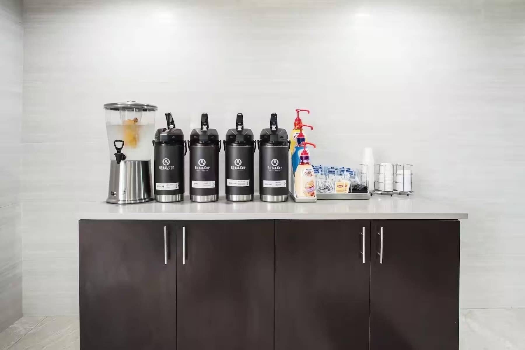 A countertop with coffee makers, a milk frother, and a coffee machine.