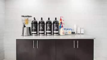 A countertop with coffee makers, a milk frother, and a coffee machine.