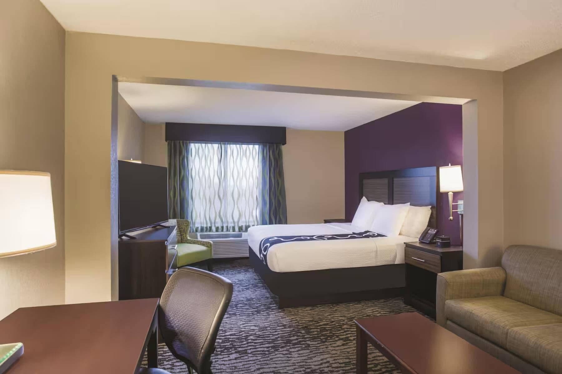 A hotel room with a bed, desk, chair, and a sofa.