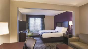 A hotel room with a bed, desk, chair, and a sofa.