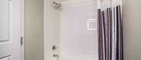 Une salle de bain équipée d’une douche, d’une baignoire et d’un rideau de douche orné de motifs ou d’inscriptions.
