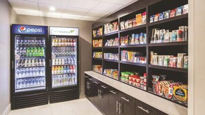 Un área de venta automática con máquinas de Pepsi y HelloGoodness, y estantes llenos de bocadillos, bebidas y productos de cuidado personal.