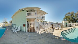 A pool area with two pools, lounge chairs, and a two-story building with a balcony. - Key West Inn Fairhope Al (Fairhope)