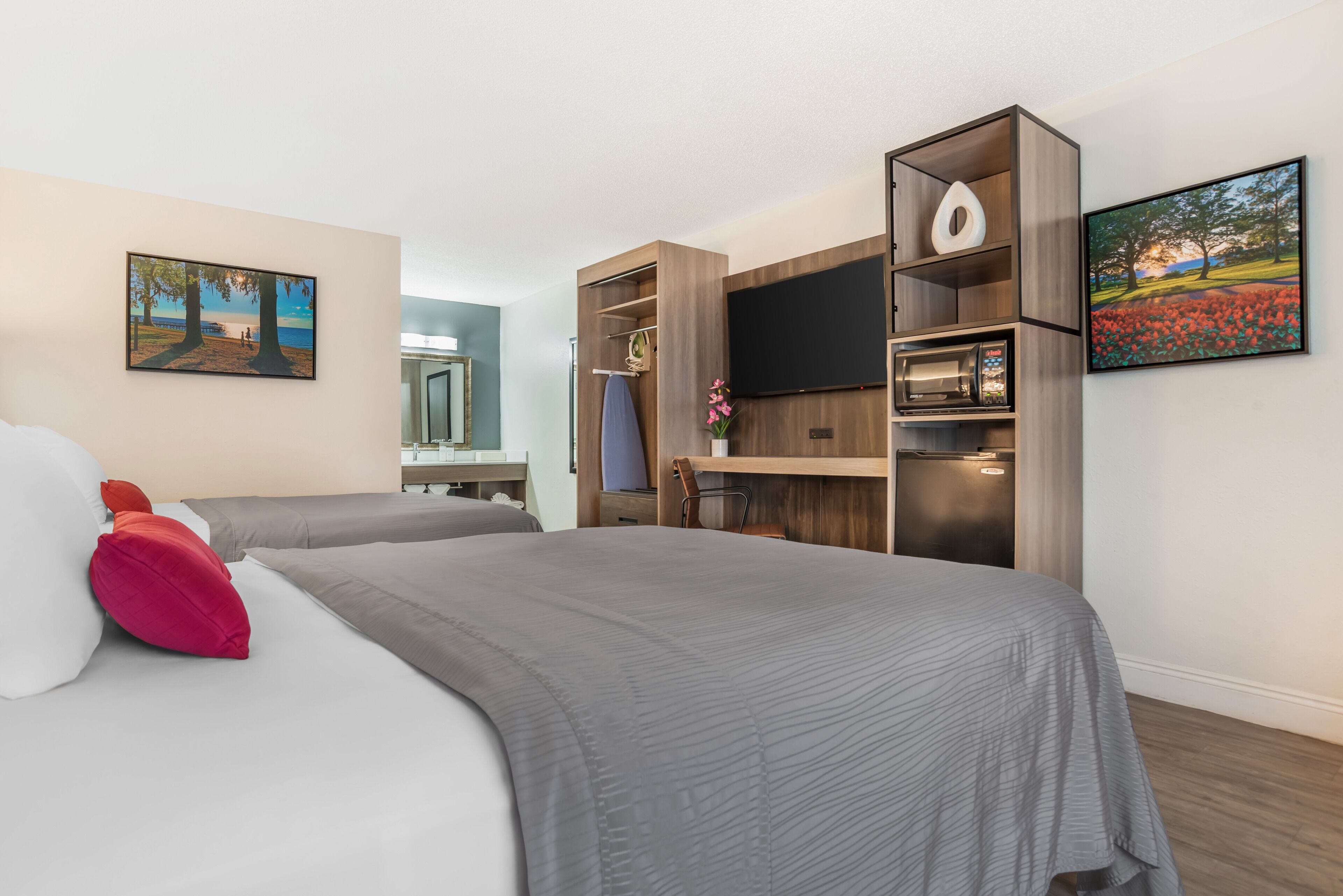 Habitación de hotel con dos camas, un televisor de pantalla plana, un microondas y un armario de madera.