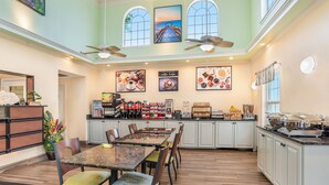 A spacious kitchen with high ceilings, large windows, and a dining area with multiple chairs and a table. - Key West Inn Fairhope Al (Fairhope)