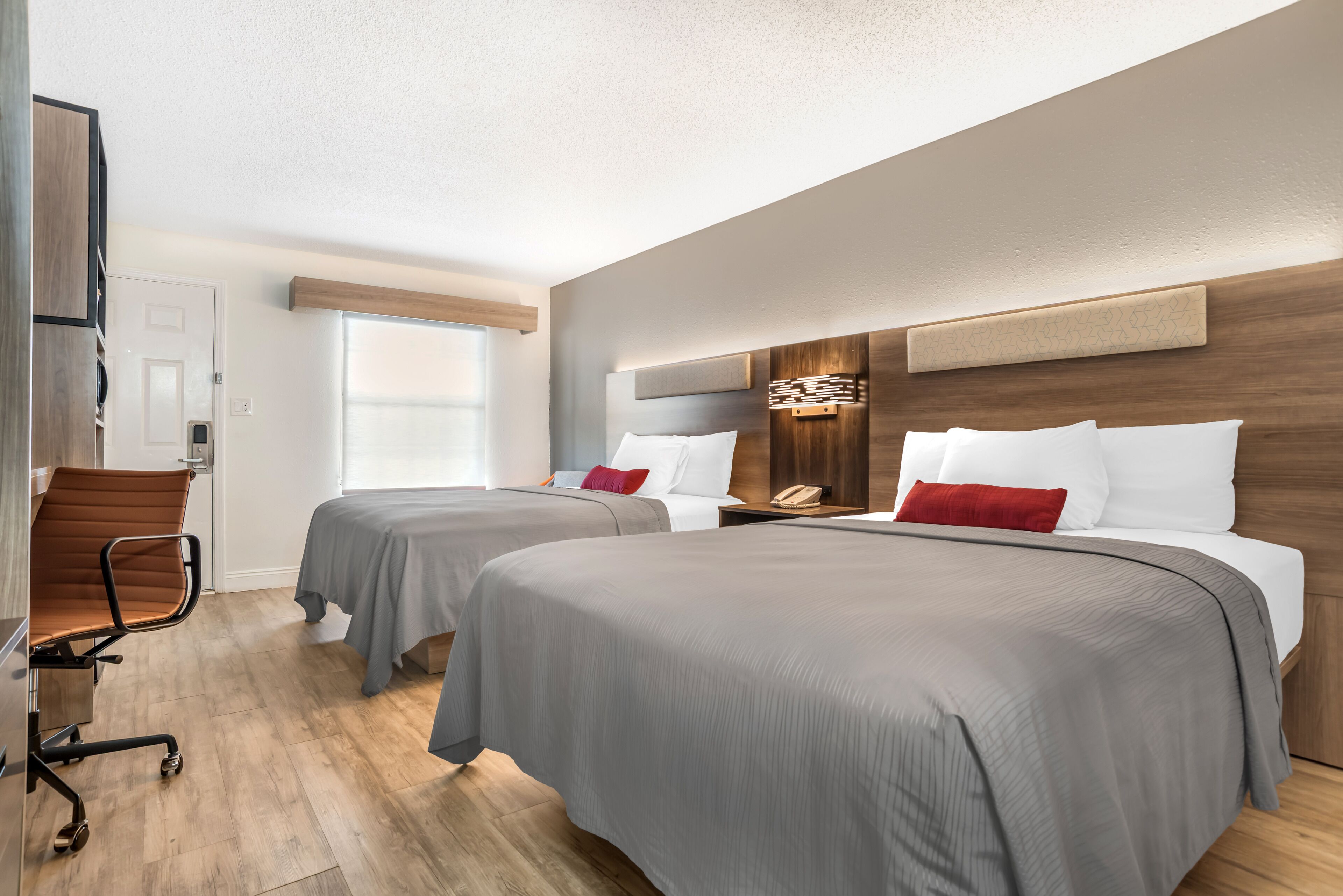 A hotel room with two beds, a desk, and a chair.