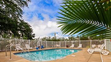 Relax by the pool surrounded by lush greenery and comfortable lounge chairs.