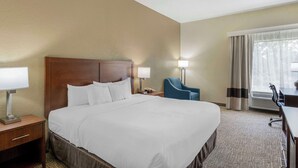A hotel room with a large bed, a desk, a chair, and a window with curtains. - Comfort Inn & Suites La Grange - Louisville Area (La Grange)