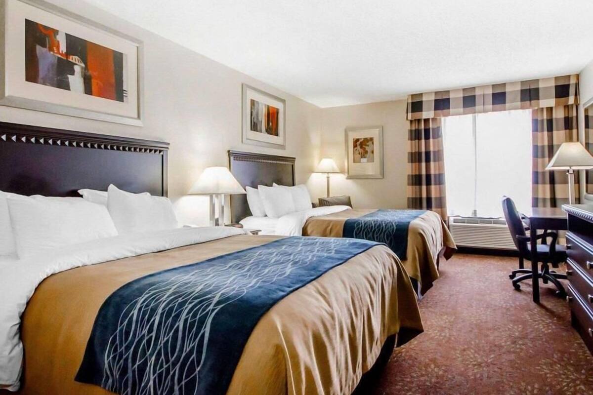 Habitación de hotel con dos camas, un escritorio y una silla.