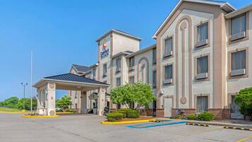 Experience the sleek, modern design of this hotel, featuring a central entrance under a covered canopy and convenient parking with designated spaces.