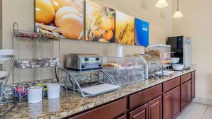 A hotel breakfast area with a buffet setup, including a toaster, a bread machine, and a cereal dispenser. - Comfort Inn & Suites La Grange - Louisville Area (La Grange)