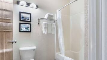 A bathroom with a toilet, a bathtub, a shower curtain, and two framed pictures on the wall.