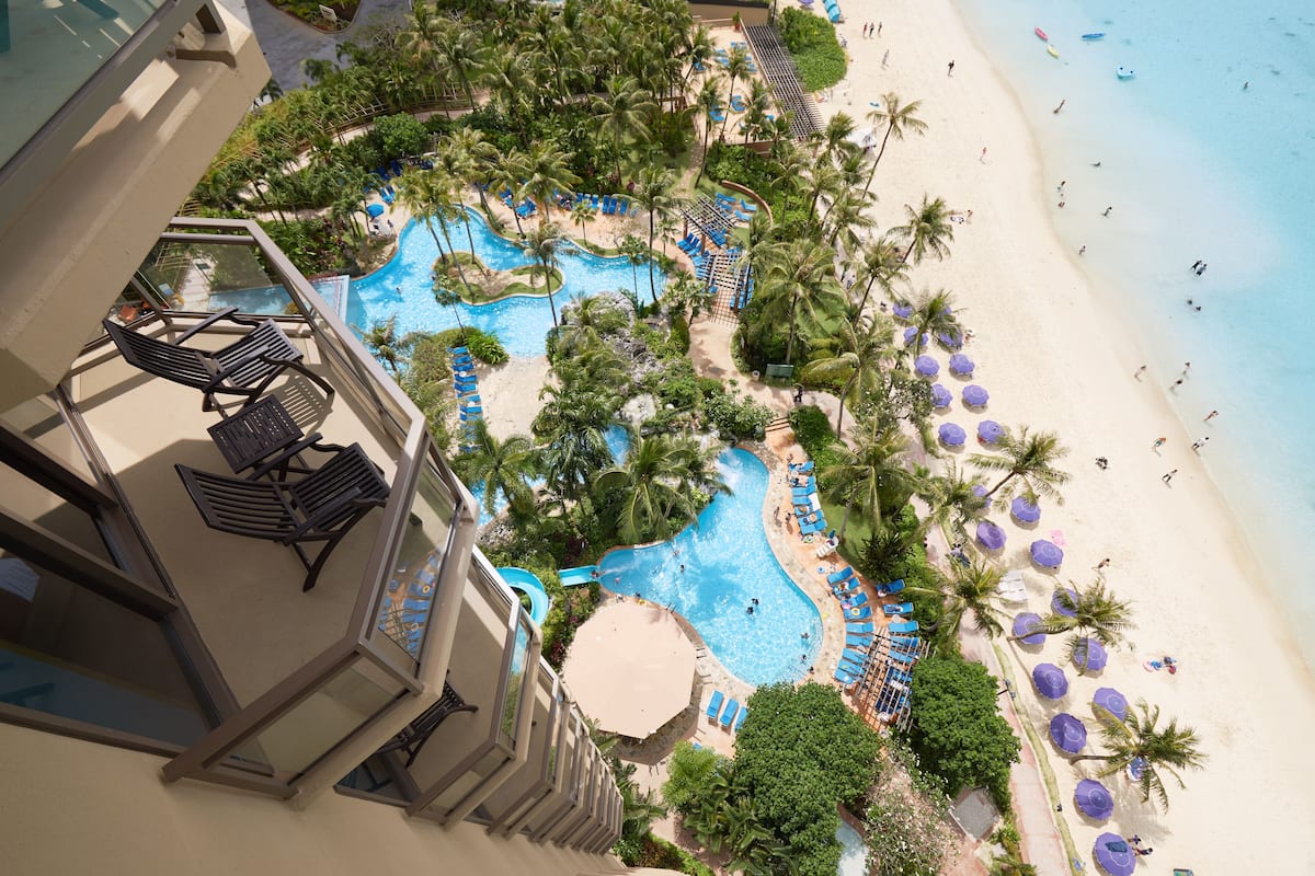 A resort with a large pool area, palm trees, and beach access.