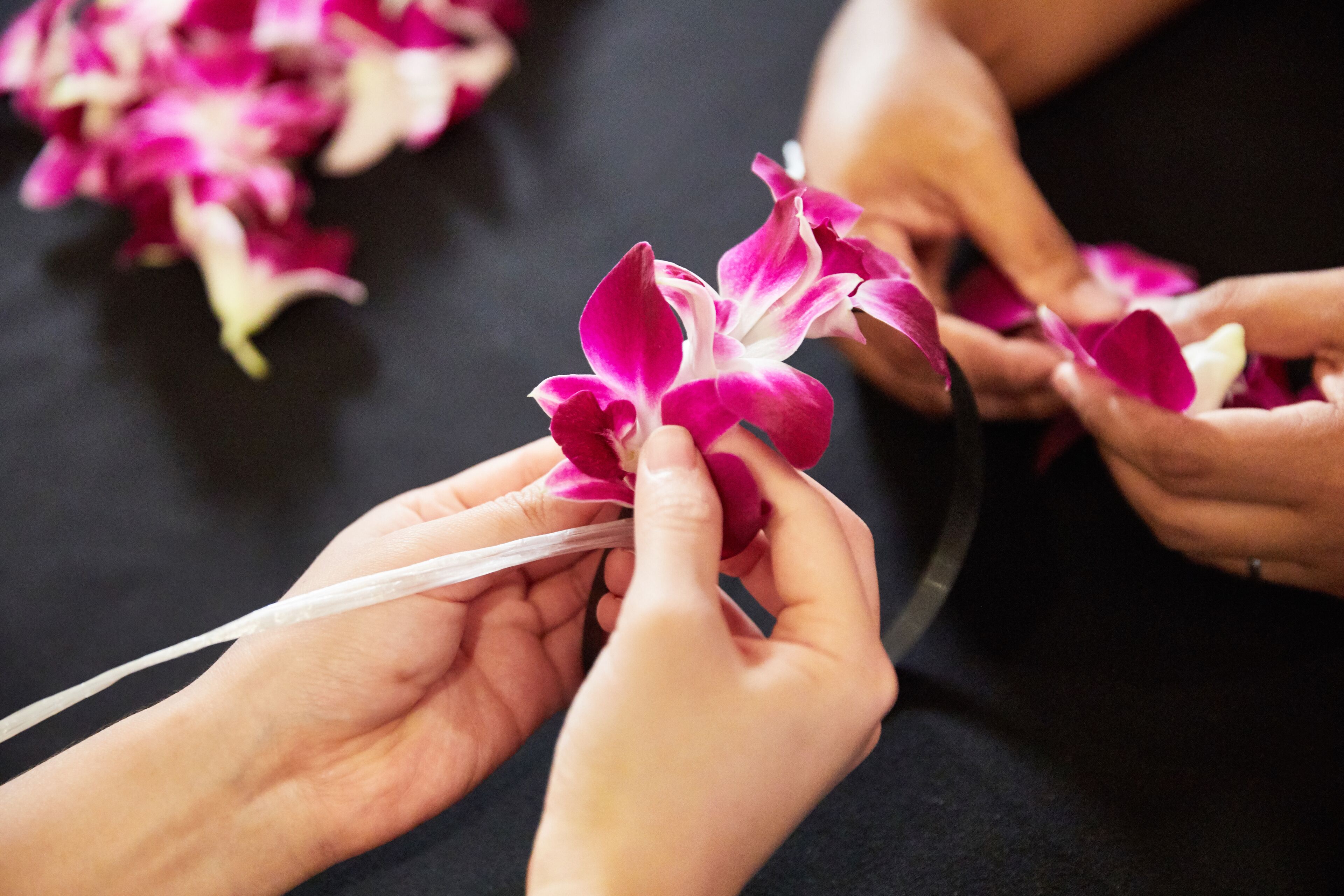 Hands holding and arranging pink and white flowers.