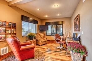 A well-lit room with a leather armchair, a wooden desk with a computer, a television, and a bookshelf with books and decorative items. - Rory & Ryan Inn (Hines)