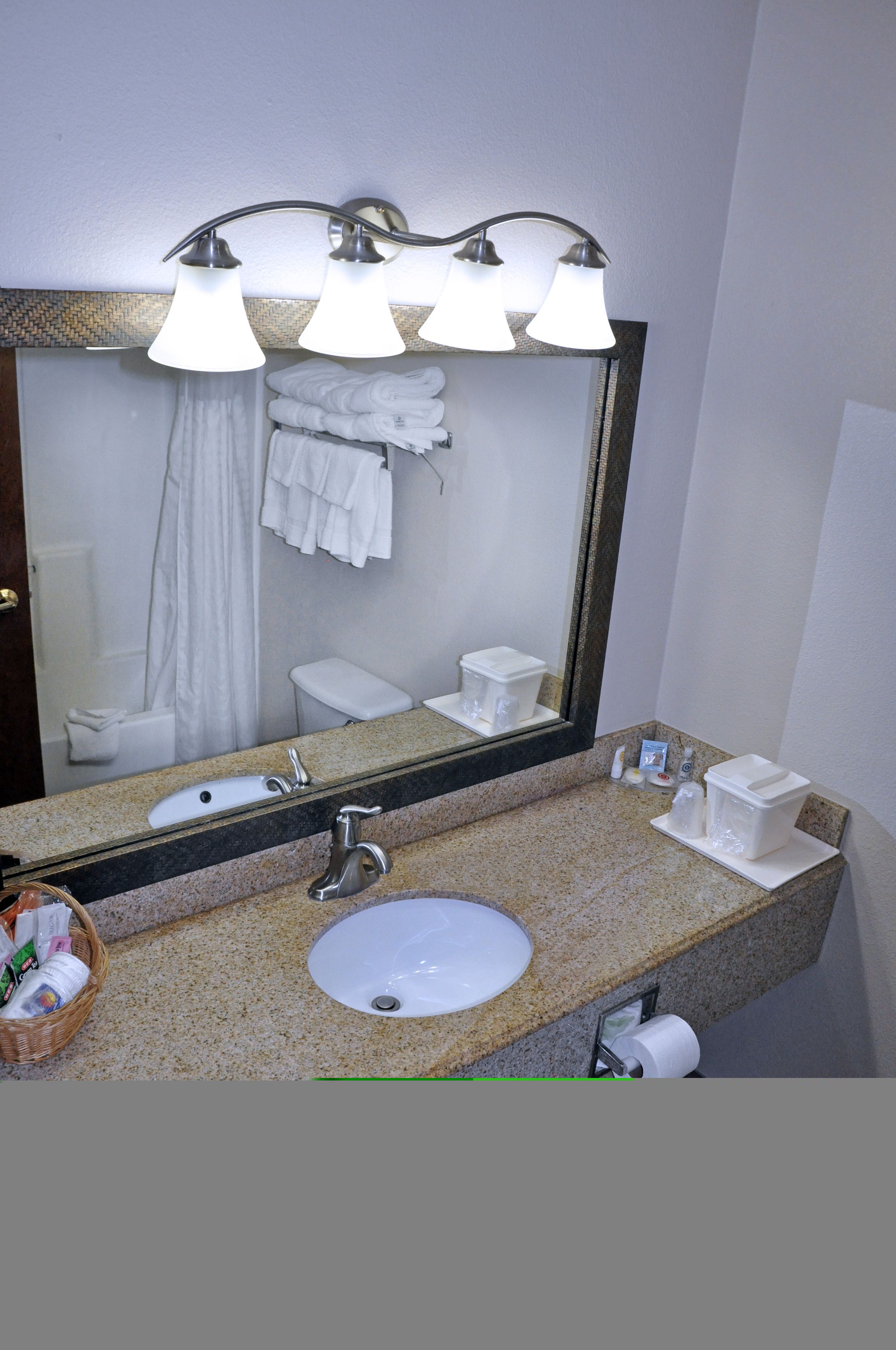 Un baño con encimera de granito, lavamanos, espejo y cortina de ducha.