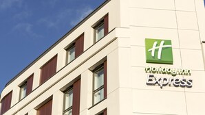 A Holiday Inn Express building with a modern design, featuring a prominent green logo and the name on the facade.