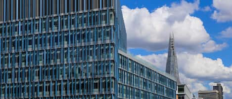 Un edificio moderno con una cuadrícula de ventanas y una torre destacada al fondo.