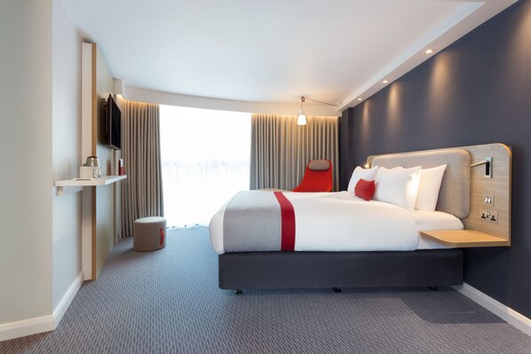 A modern hotel room with a large bed, a flat-screen TV mounted on the wall, a small table, and a window with curtains. - Holiday Inn Express London - Southwark by IHG (London)