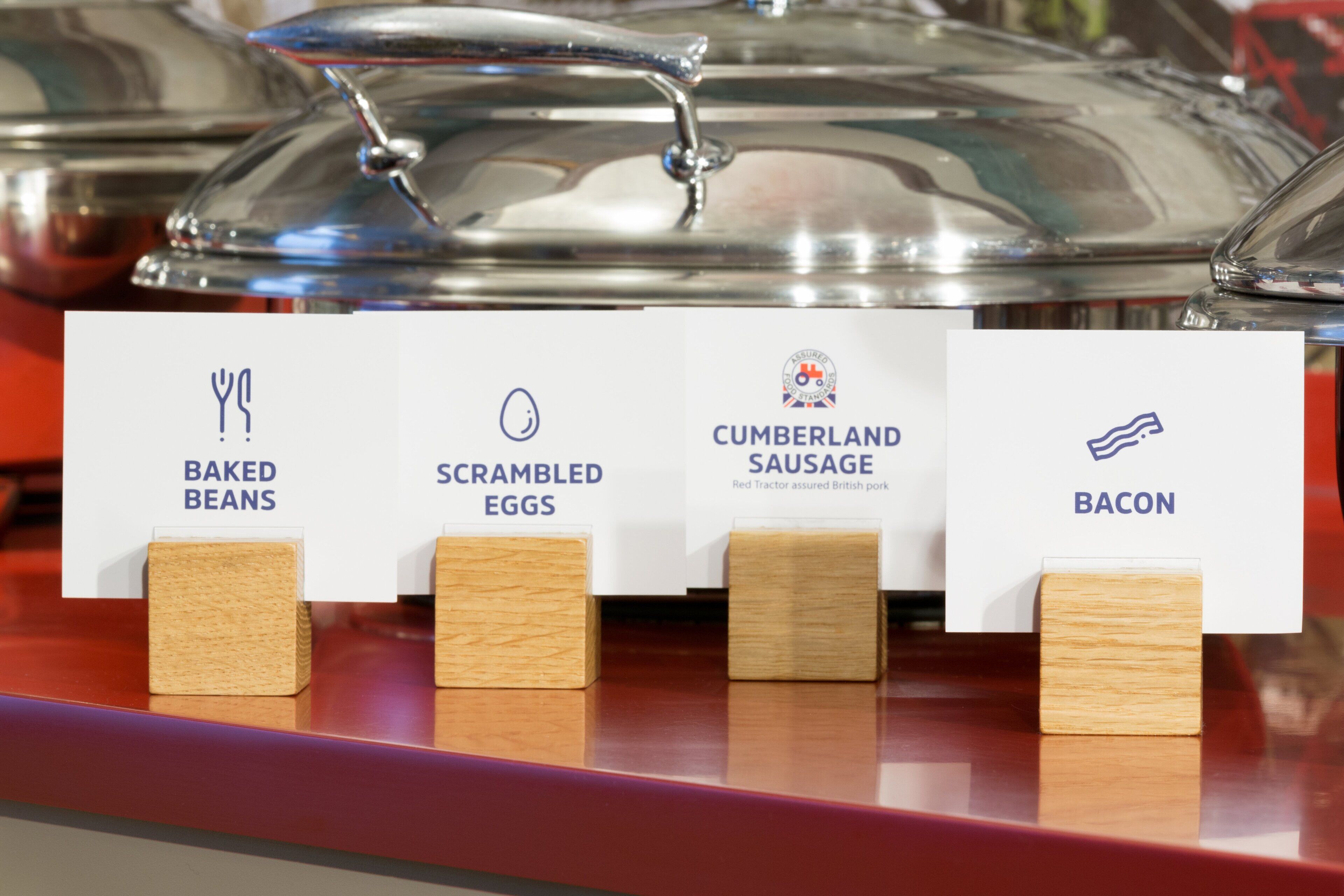 Mostra de plats amb etiquetes per febrons, ous remenats, botifarra Cumberland i bacon.