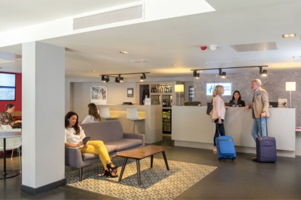 A modern lobby with seating areas, a reception desk, and a bar.