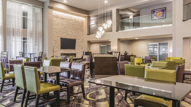 A hotel lobby with multiple dining areas, a flat-screen TV, and a staircase to an upper level. - La Quinta Inn & Suites by Wyndham Atlanta Perimeter Medical (Atlanta)