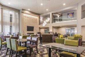 A hotel lobby with multiple dining areas, a flat-screen TV, and a staircase to an upper level. - La Quinta Inn & Suites by Wyndham Atlanta Perimeter Medical (Atlanta)