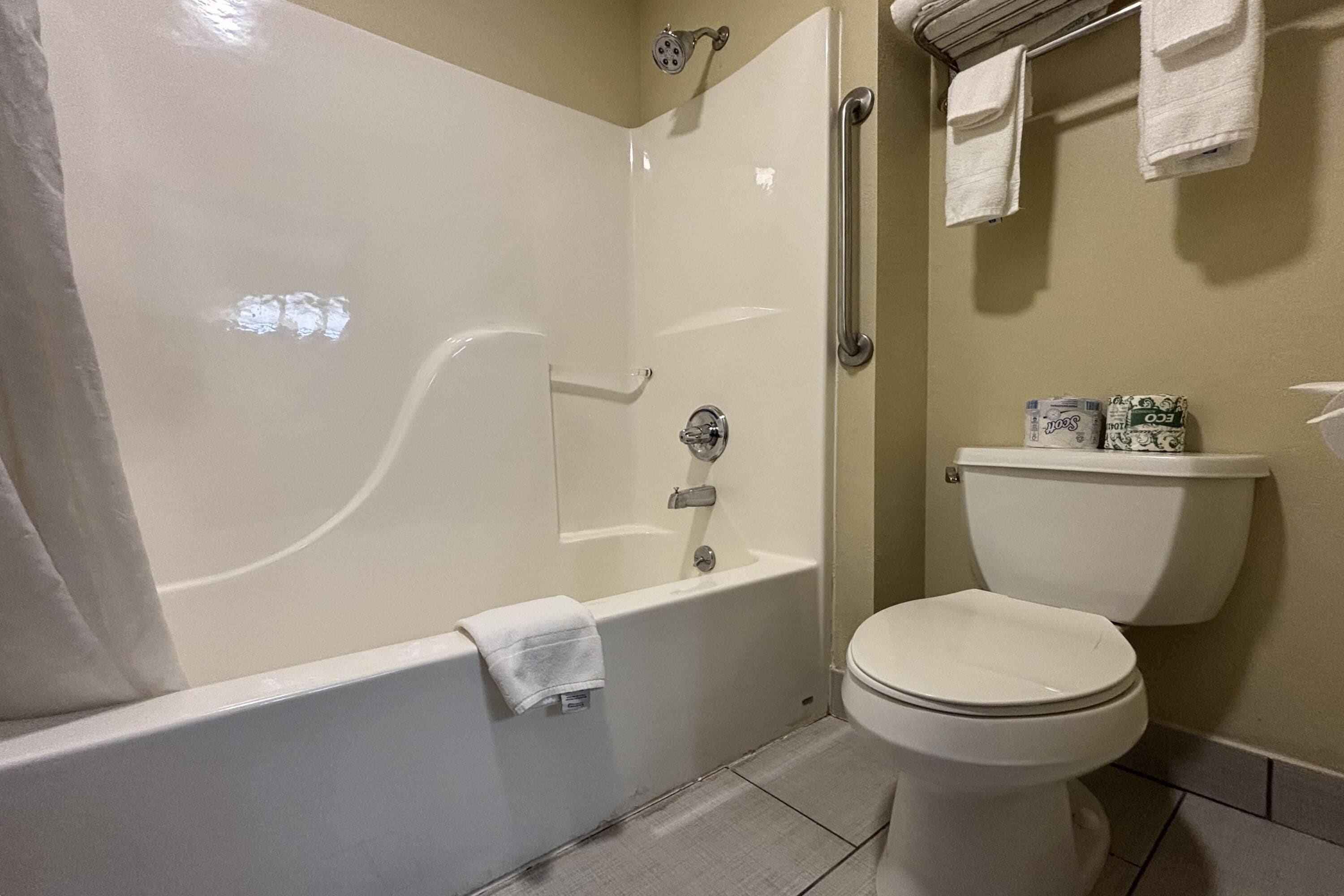 A bathroom with a bathtub, toilet, and a towel rack.