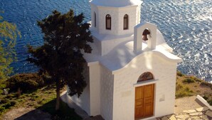 A small white church with a bell tower, a wooden door, and a cross on top.