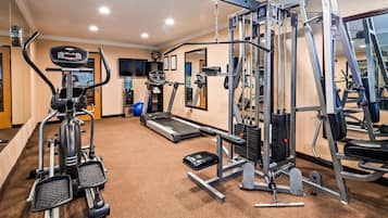 Un gimnasio con cintas de correr, elípticas y equipos de levantamiento de pesas.